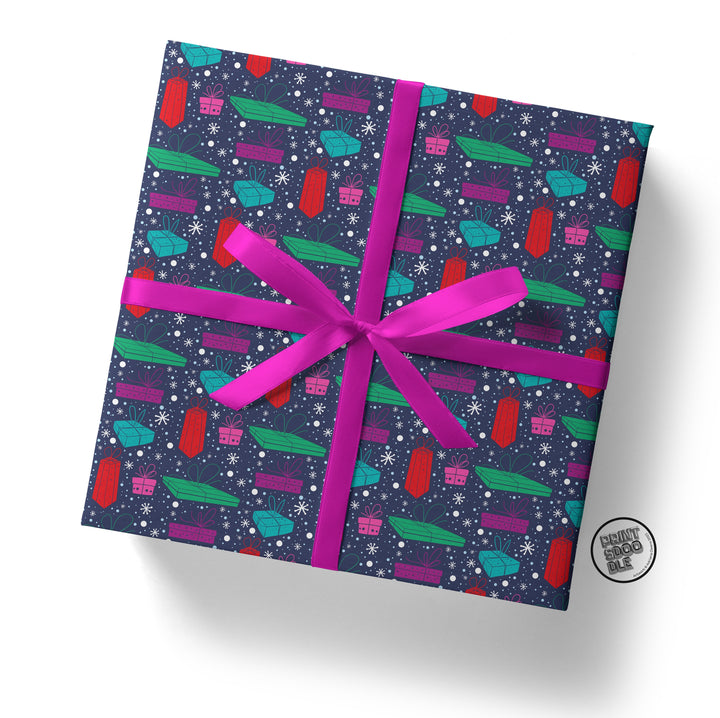 A square gift box enveloped in Christmas Pressie Gift Wrap, showcasing a vibrant, vintage space theme with planets, rockets, and stars. Tied with a bright pink bow, it makes an ideal Secret Santa surprise as it rests against a plain white background.